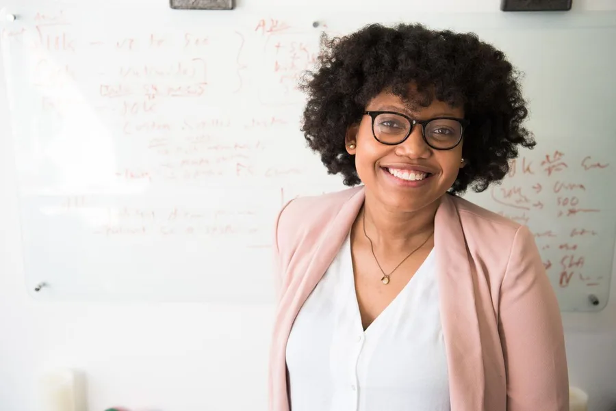 Adult woman in an office setting beside a whiteboard, editorial stock portrait